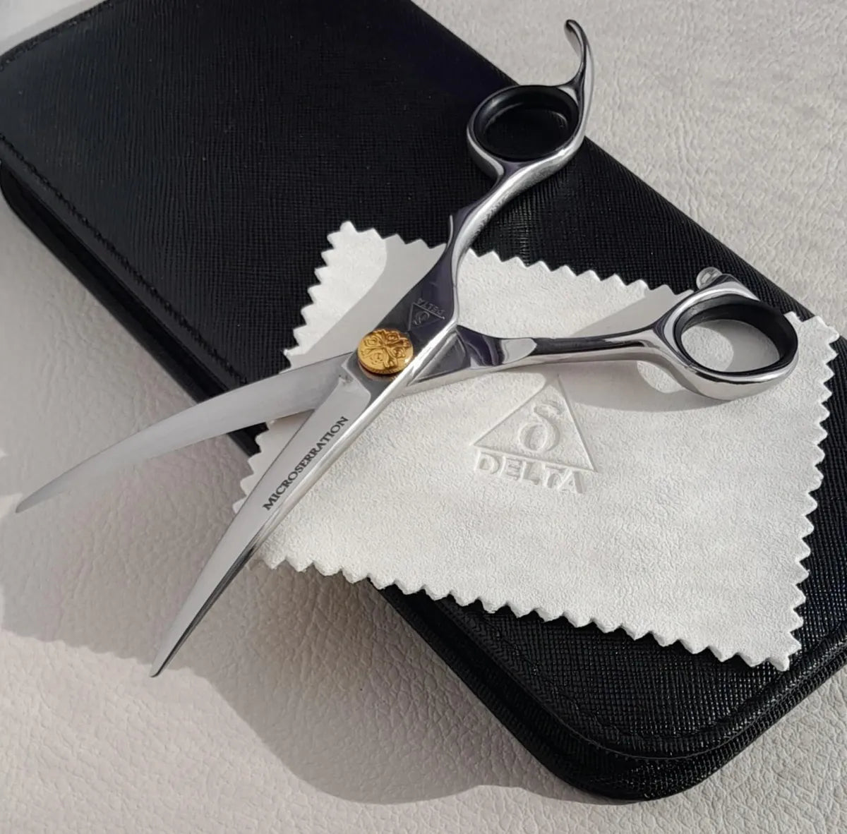 Delta Asian Curve 6-inch dog grooming scissor with micro serration blade open sitting on top of black scissor case